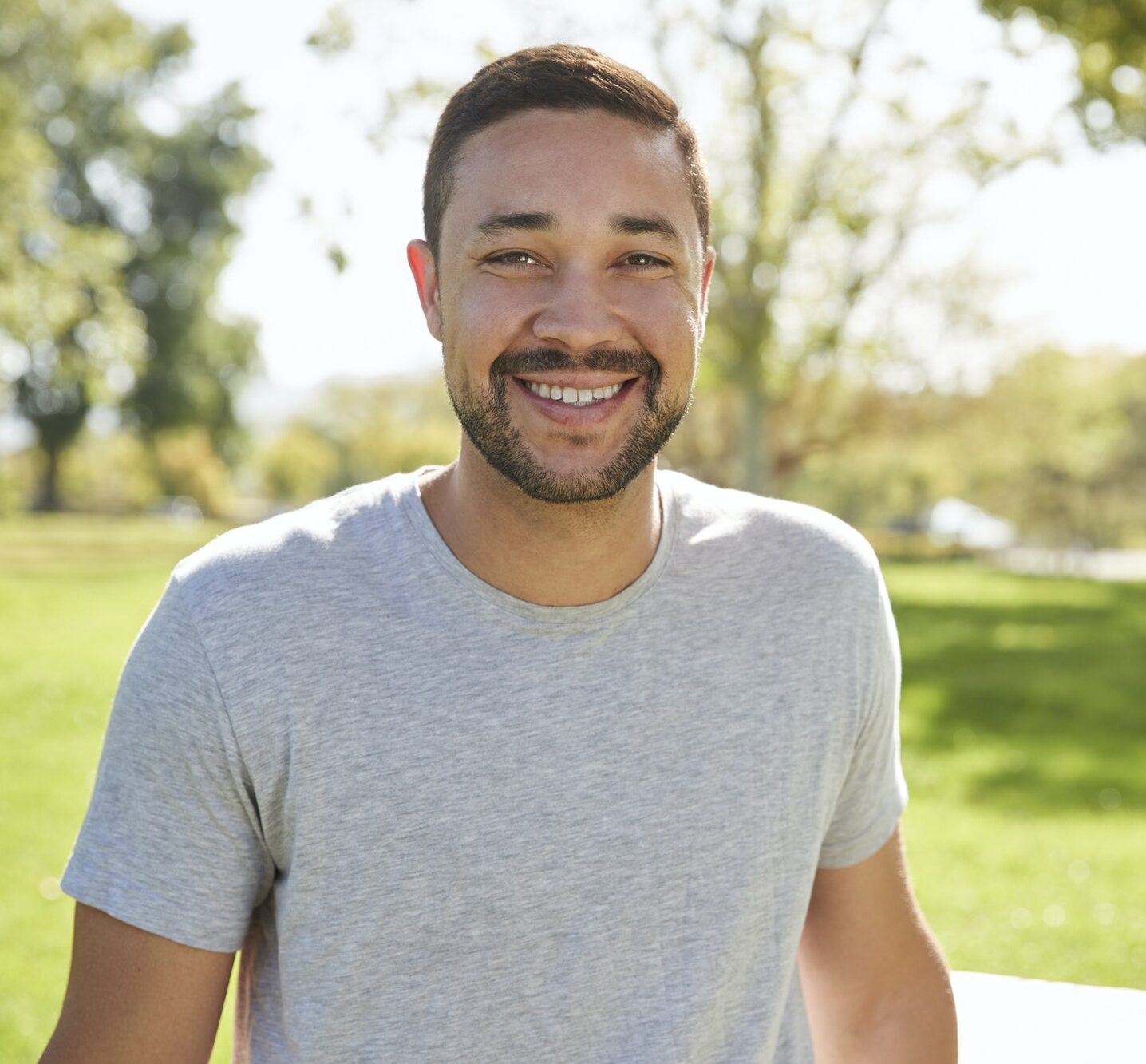 Outdoor Head And Shoulders Portrait Of Smiling Man In Park